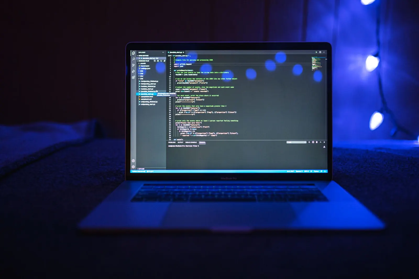 Portátil con código en pantalla, iluminado por luces azules en una habitación oscura