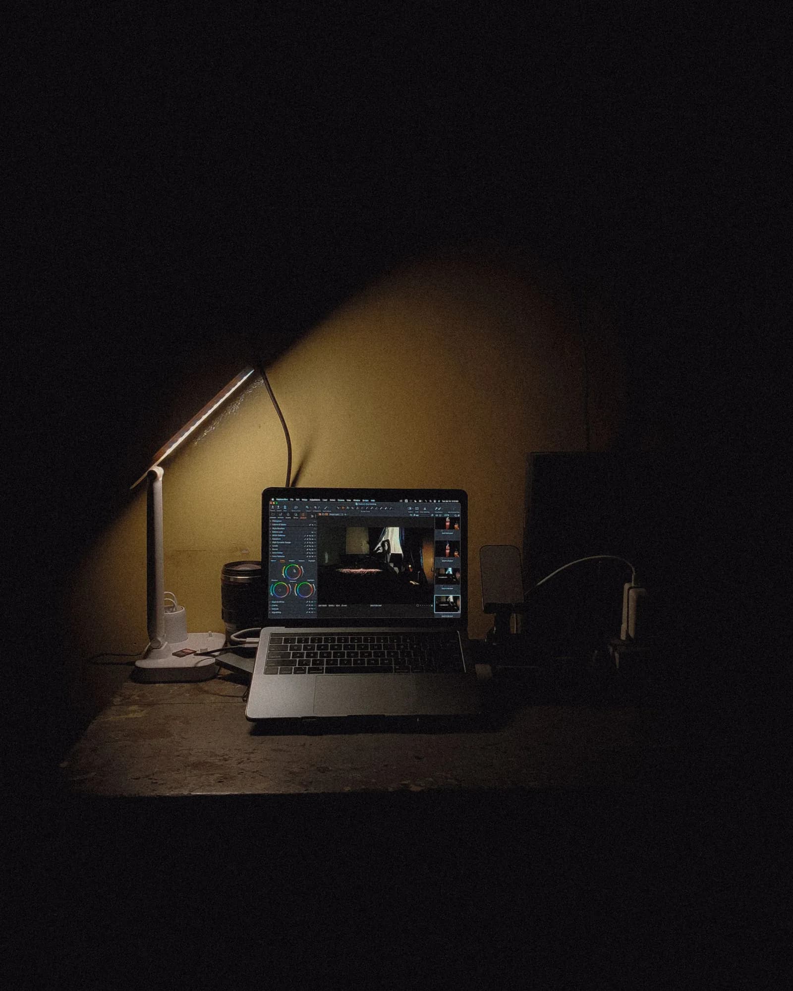 Portátil encendido sobre un escritorio en penumbra, iluminado por una lámpara